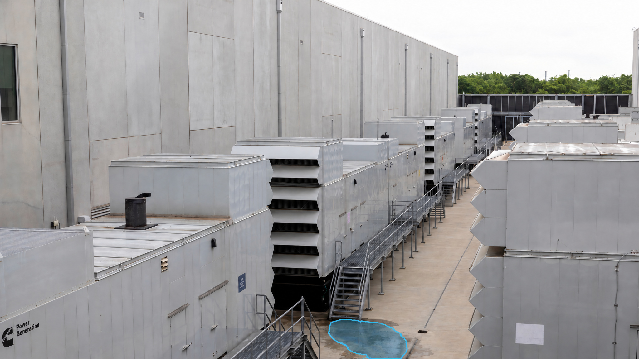 Outdoor generator yard with a blue detection overlay marking a puddle on the concrete between generator enclosures.