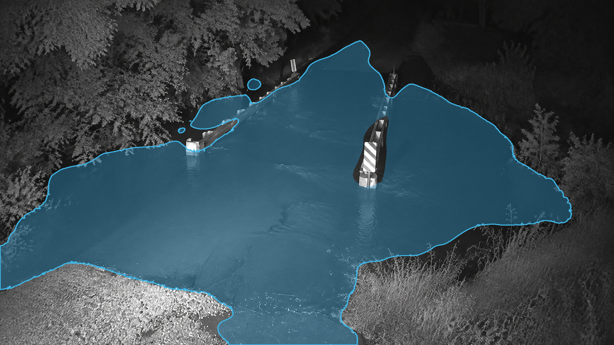 Flooded bridge in a near-infrared night frame. Blue detection overlay marks the standing water.