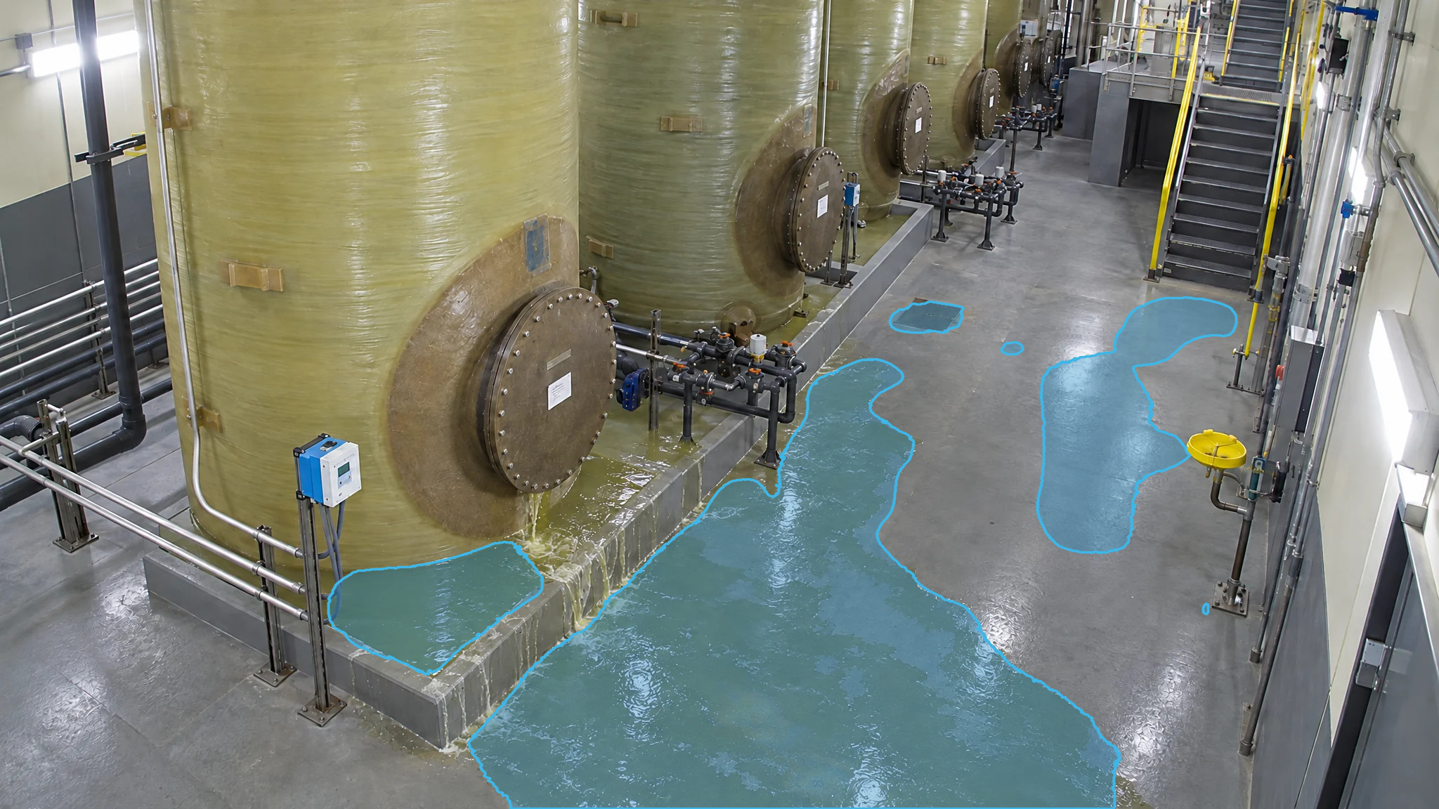 Tank room with blue detection overlays marking puddles around the tank bases and across the floor.